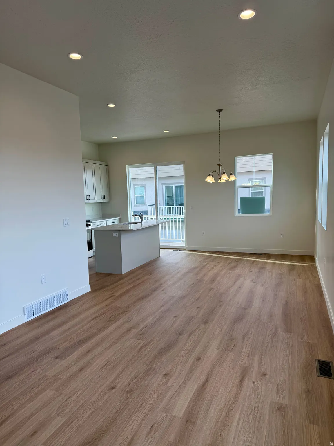 Unfurnished living room featuring recessed lighting, light wood-style flooring, and a chandelier