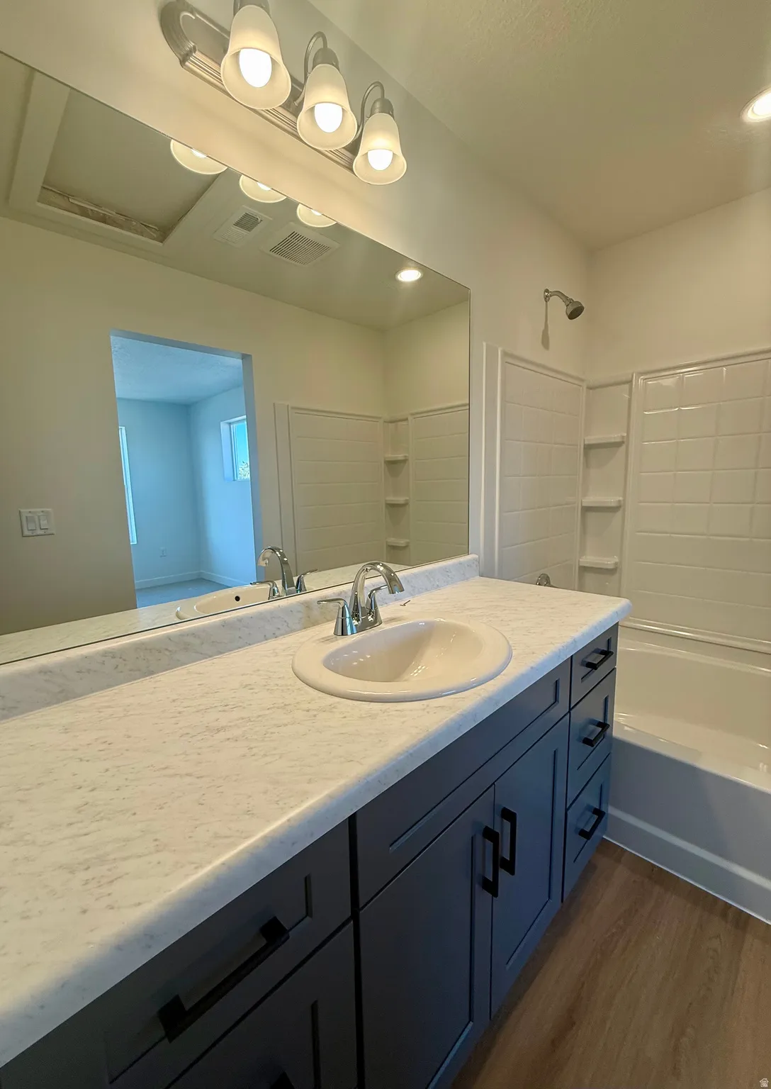 Bathroom with vanity, dark wood finished floors, and bathtub / shower combination