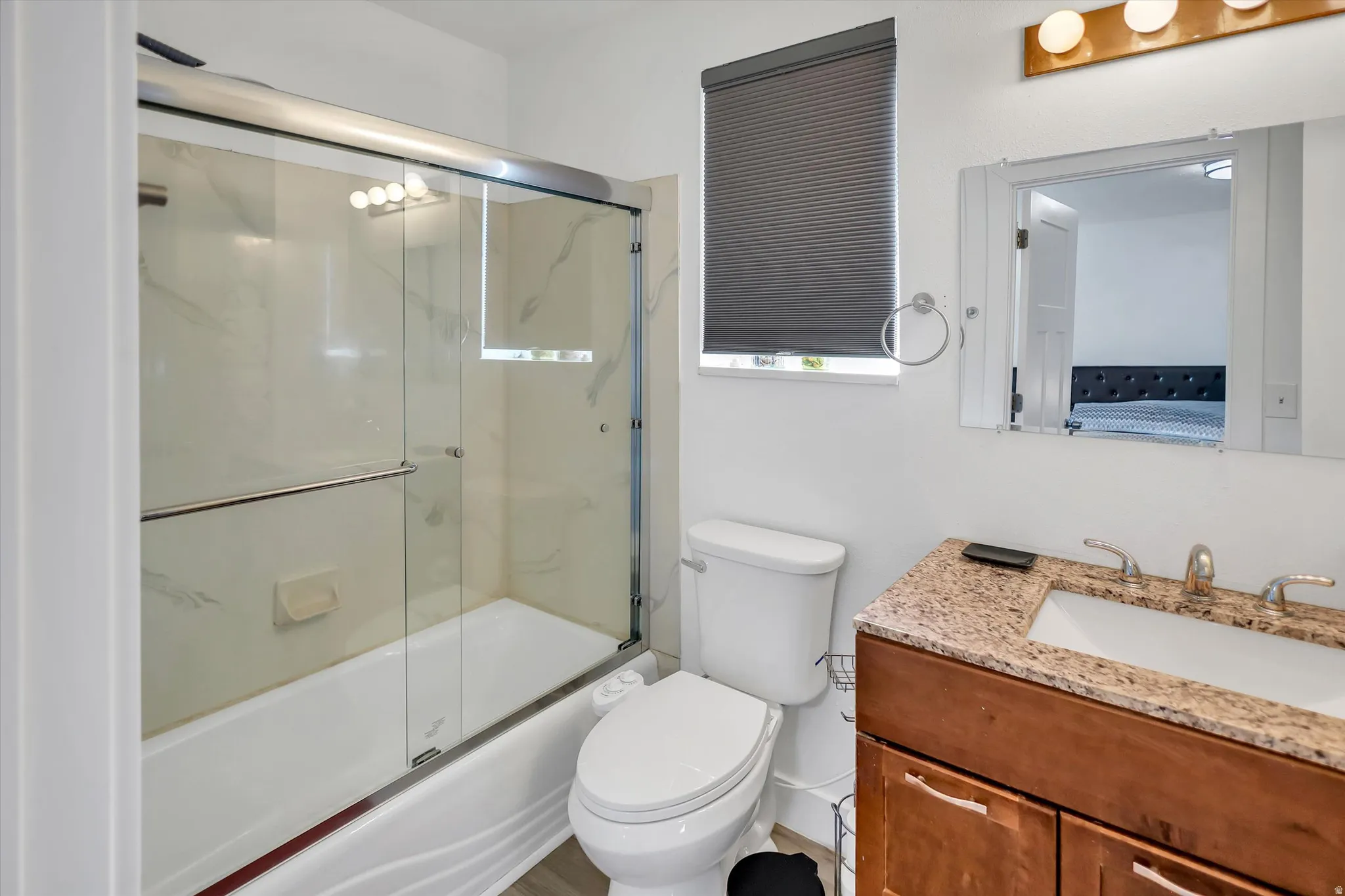 Bathroom with bath / shower combo with glass door and vanity