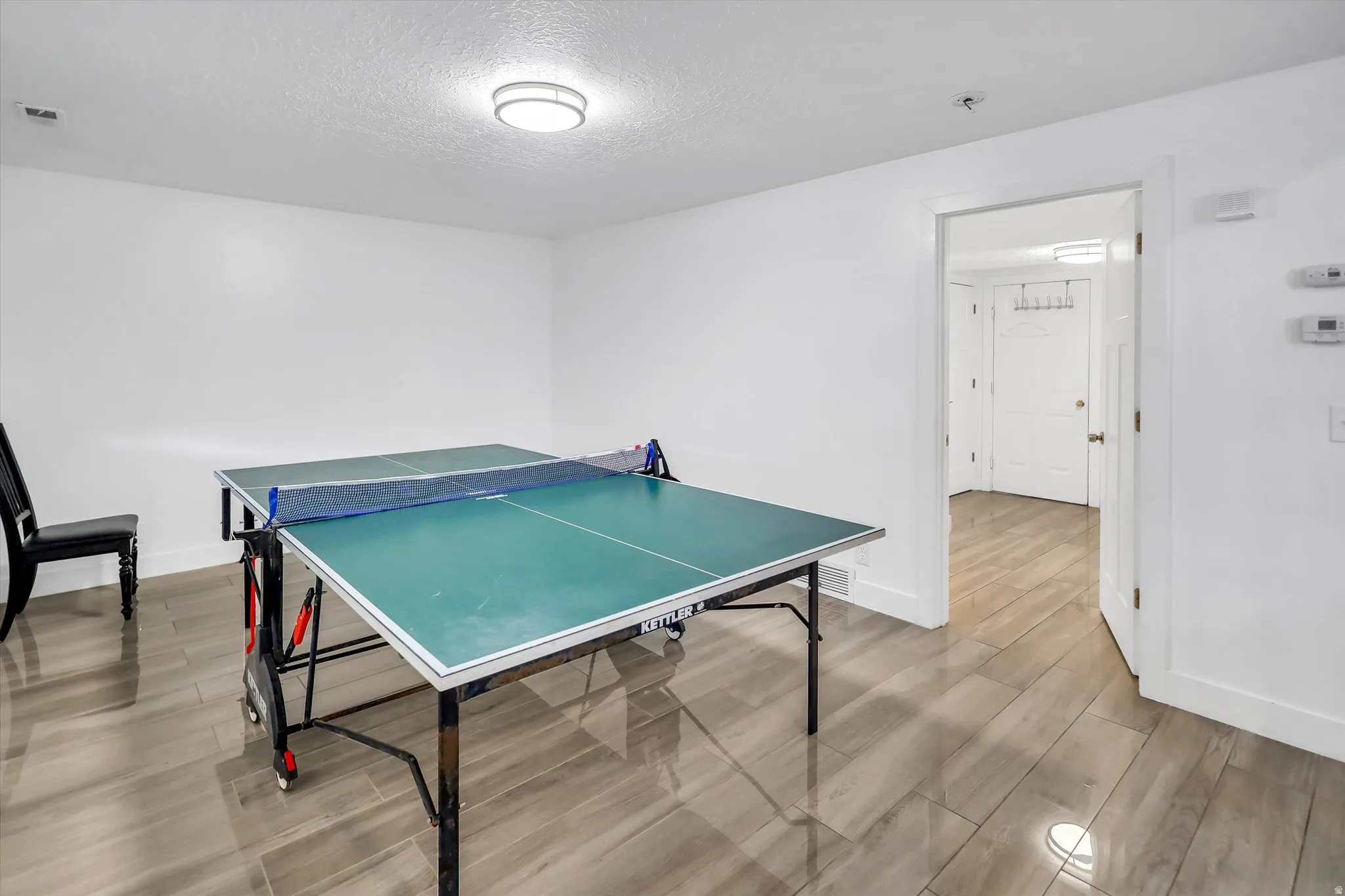 Game room featuring wood finish floors and a textured ceiling