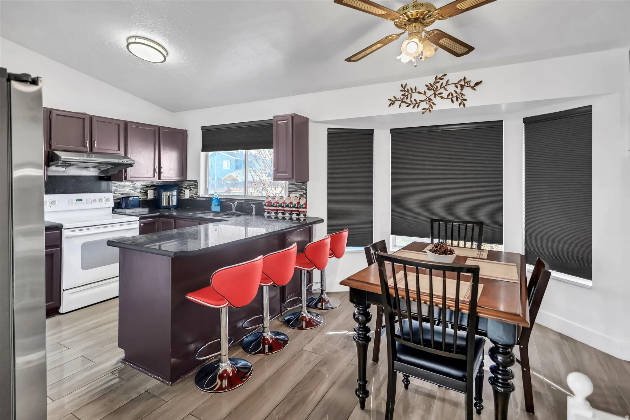 Kitchen featuring electric stove, stainless steel fridge, lofted ceiling, a kitchen bar, and a peninsula