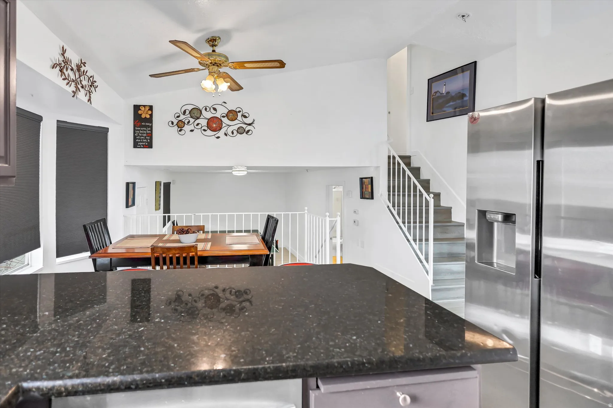 Kitchen featuring stainless steel fridge, dark stone countertops, and ceiling fan