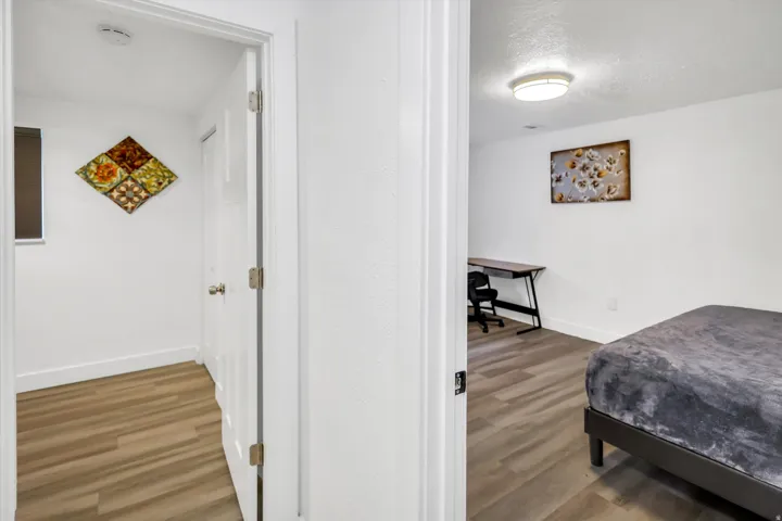 Bedroom featuring light wood finished floors, a textured ceiling, and an office area