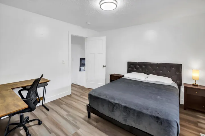 Bedroom with a desk, a textured ceiling, and wood finished floors
