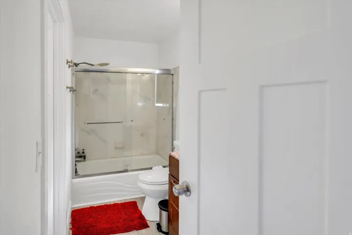 Bathroom featuring enclosed tub / shower combo, vanity, and light wood-style flooring
