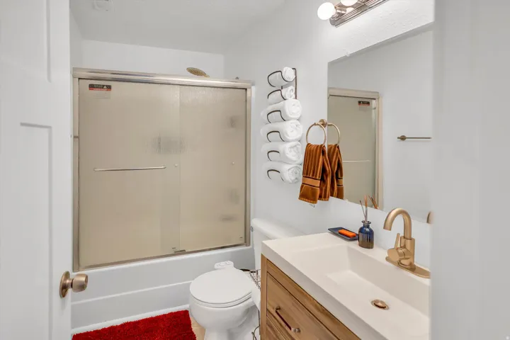 Bathroom with vanity and combined bath / shower with glass door