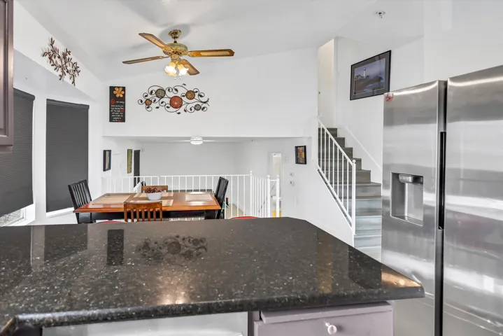 Kitchen featuring stainless steel fridge, dark stone countertops, and ceiling fan