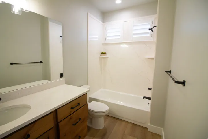 Full bath with vanity, a combined bath / shower with marble appearance, and light wood finished floors