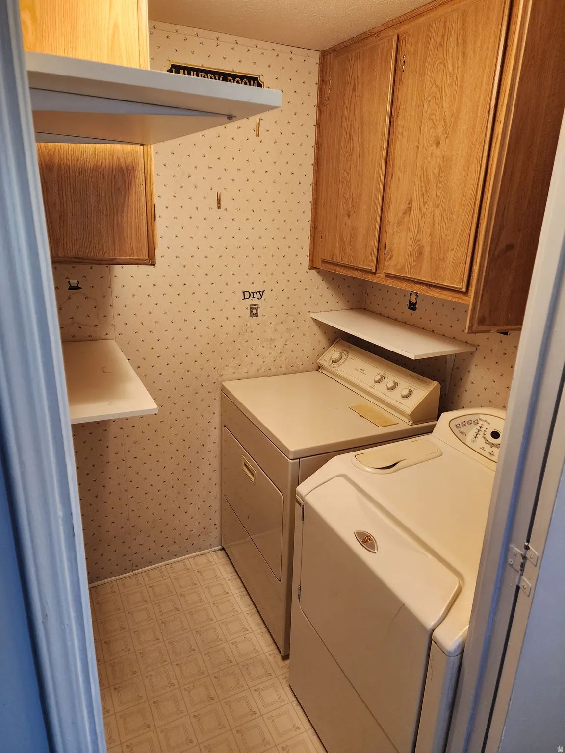 Laundry area featuring cabinet space, wallpapered walls, and separate washer and dryer