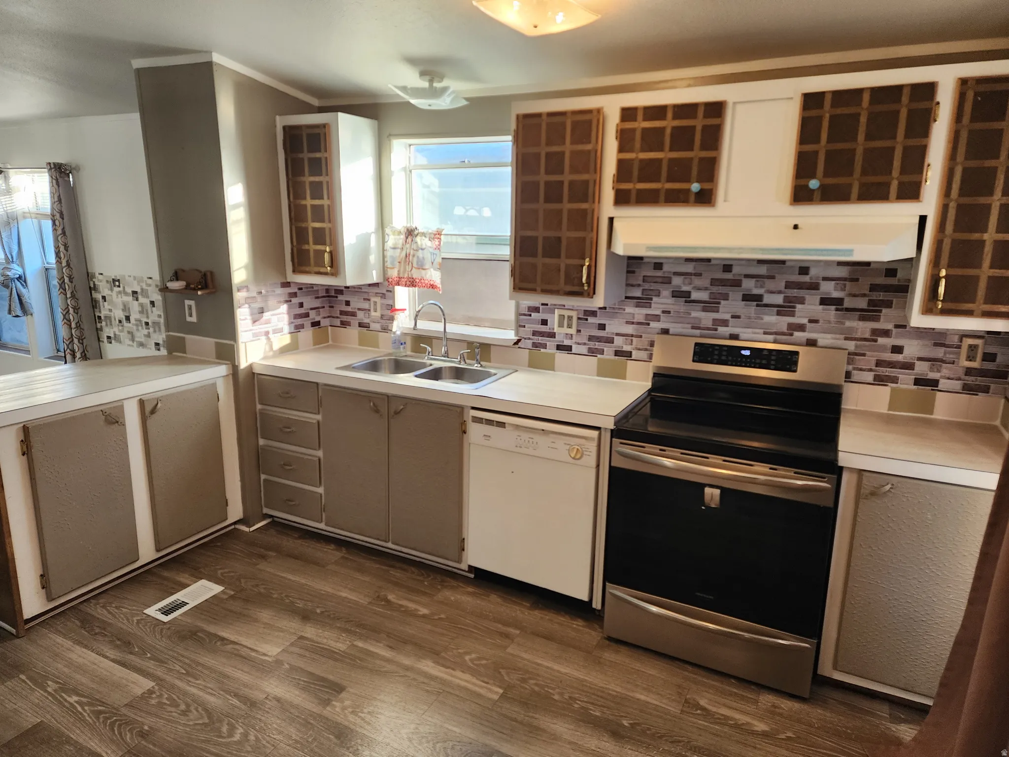 Kitchen with electric range, light countertops, dishwasher, backsplash, and crown molding