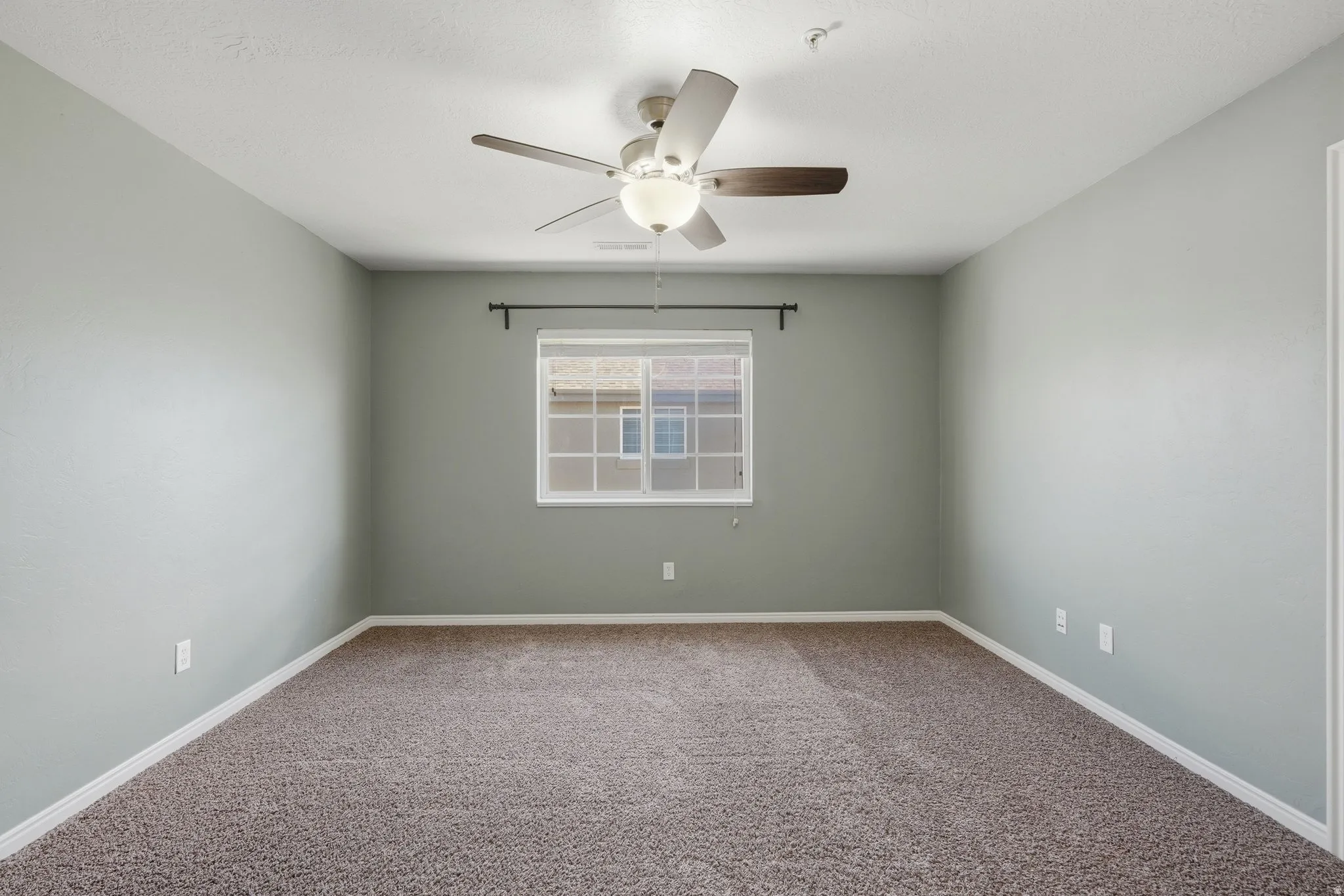 Carpeted spare room featuring a ceiling fan and baseboards