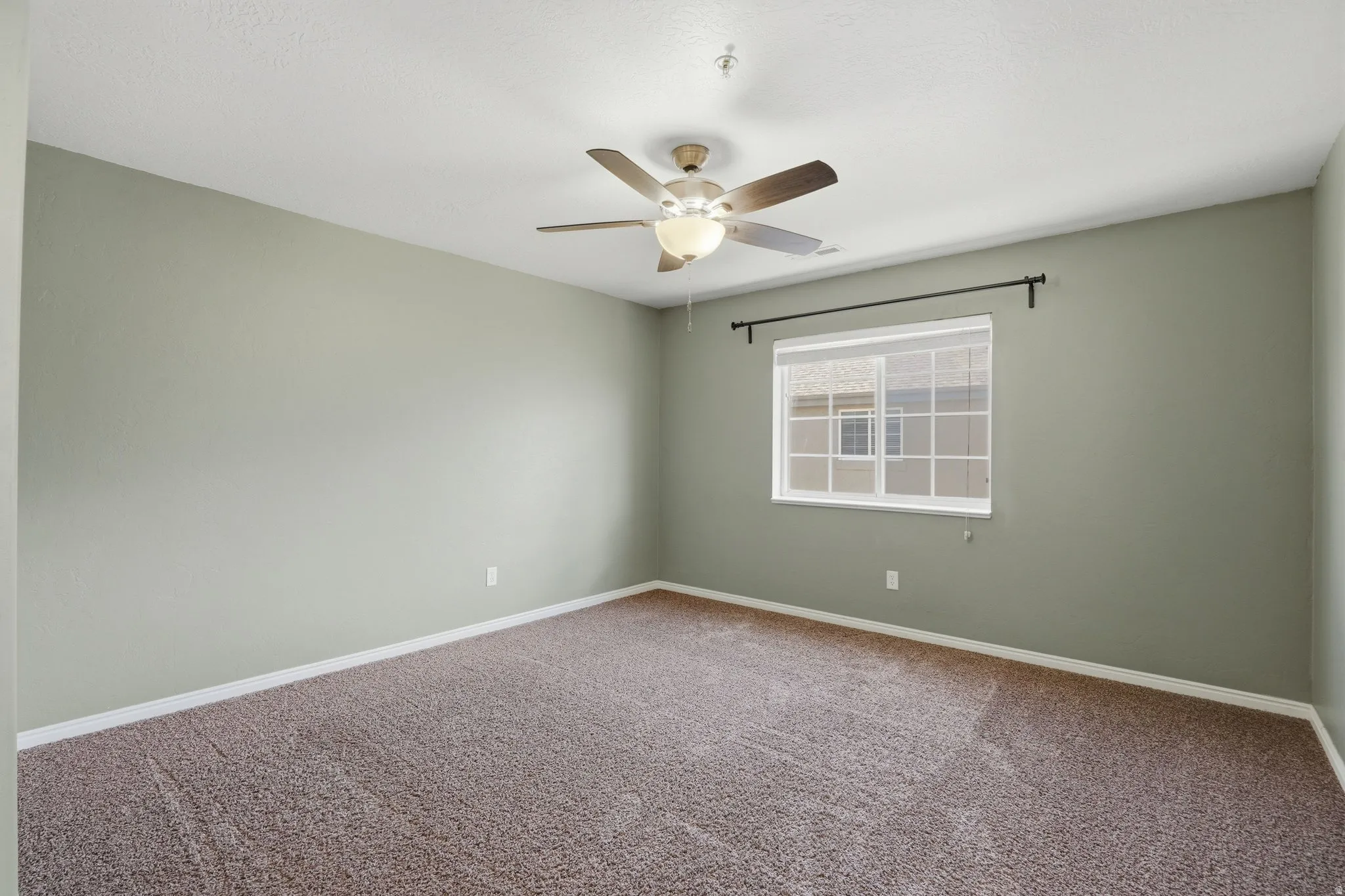 Carpeted empty room with baseboards and ceiling fan