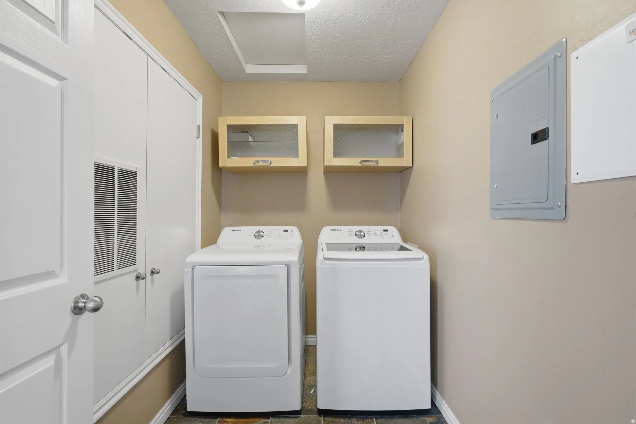 Laundry room featuring electric panel, a textured ceiling, and independent washer and dryer