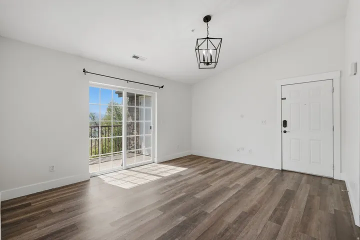 Unfurnished dining area featuring vaulted ceiling, dark wood-style flooring, and hanging lights