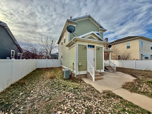 Rear view of house with a fenced backyard and entry steps