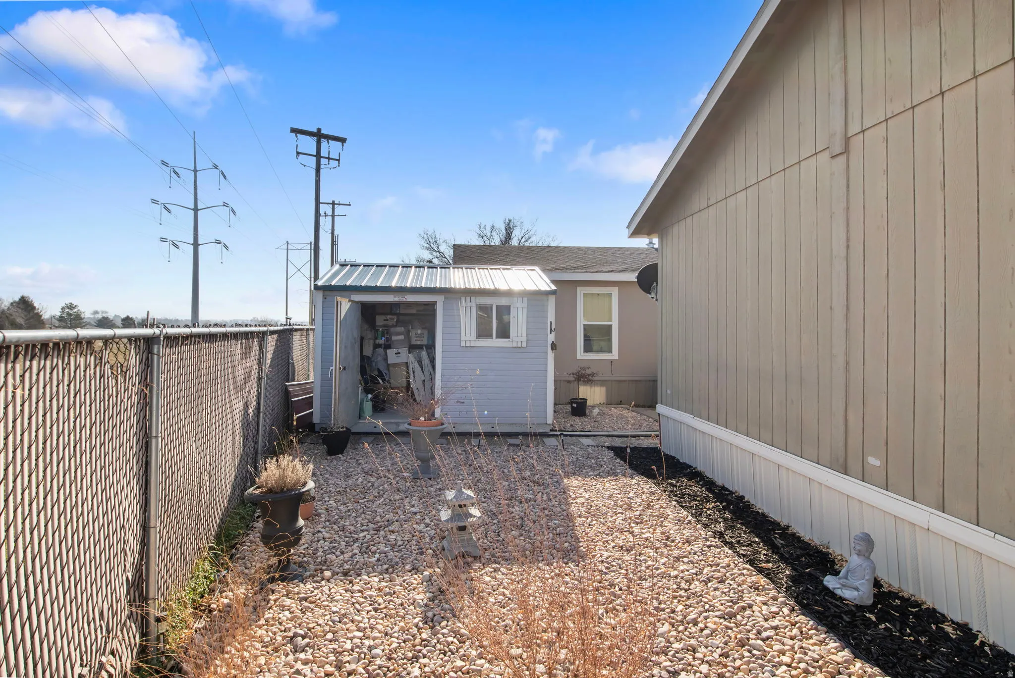 View of side of home featuring a fenced backyard and a shed