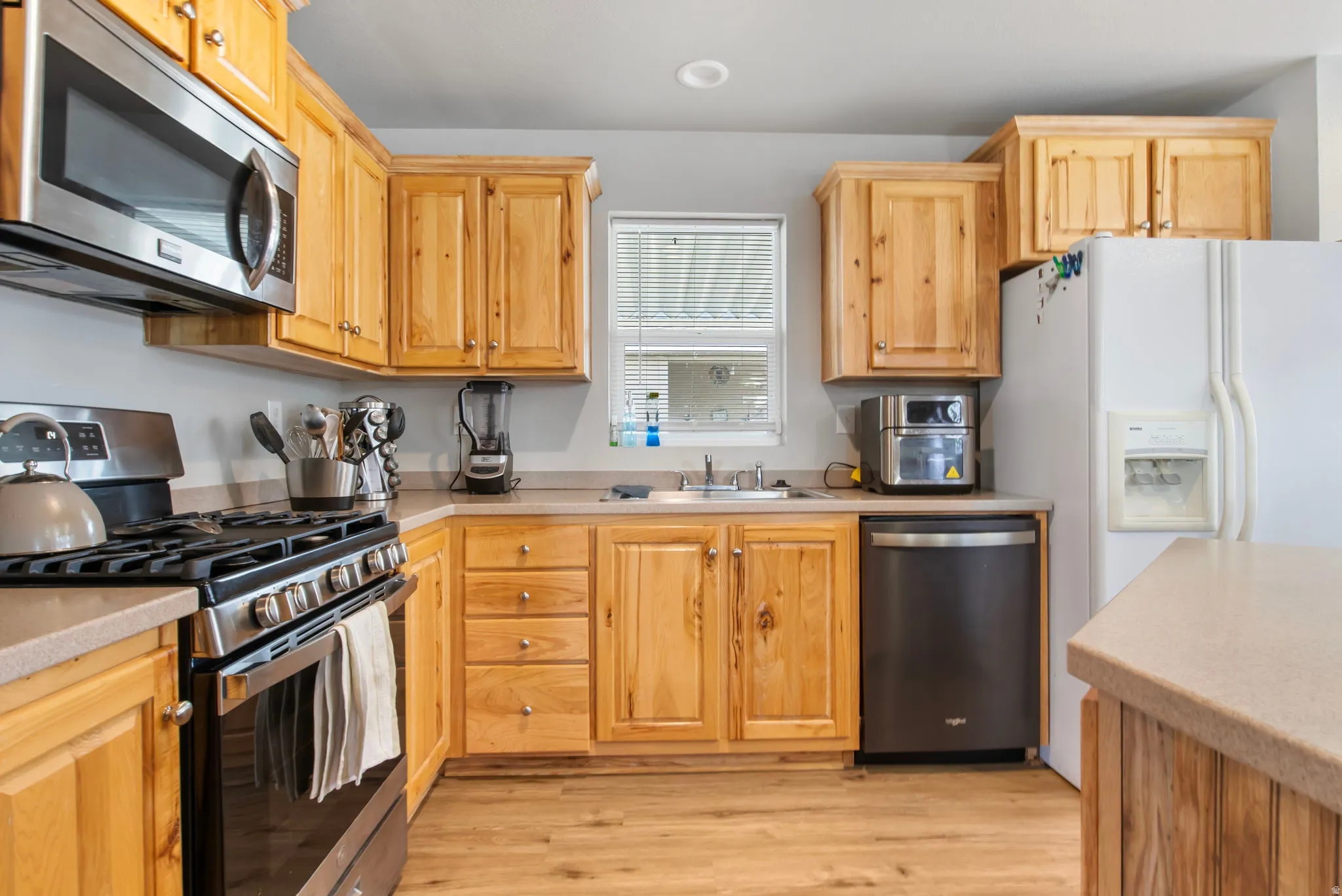 Kitchen with appliances with stainless steel finishes, light wood-type flooring, and light brown cabinetry