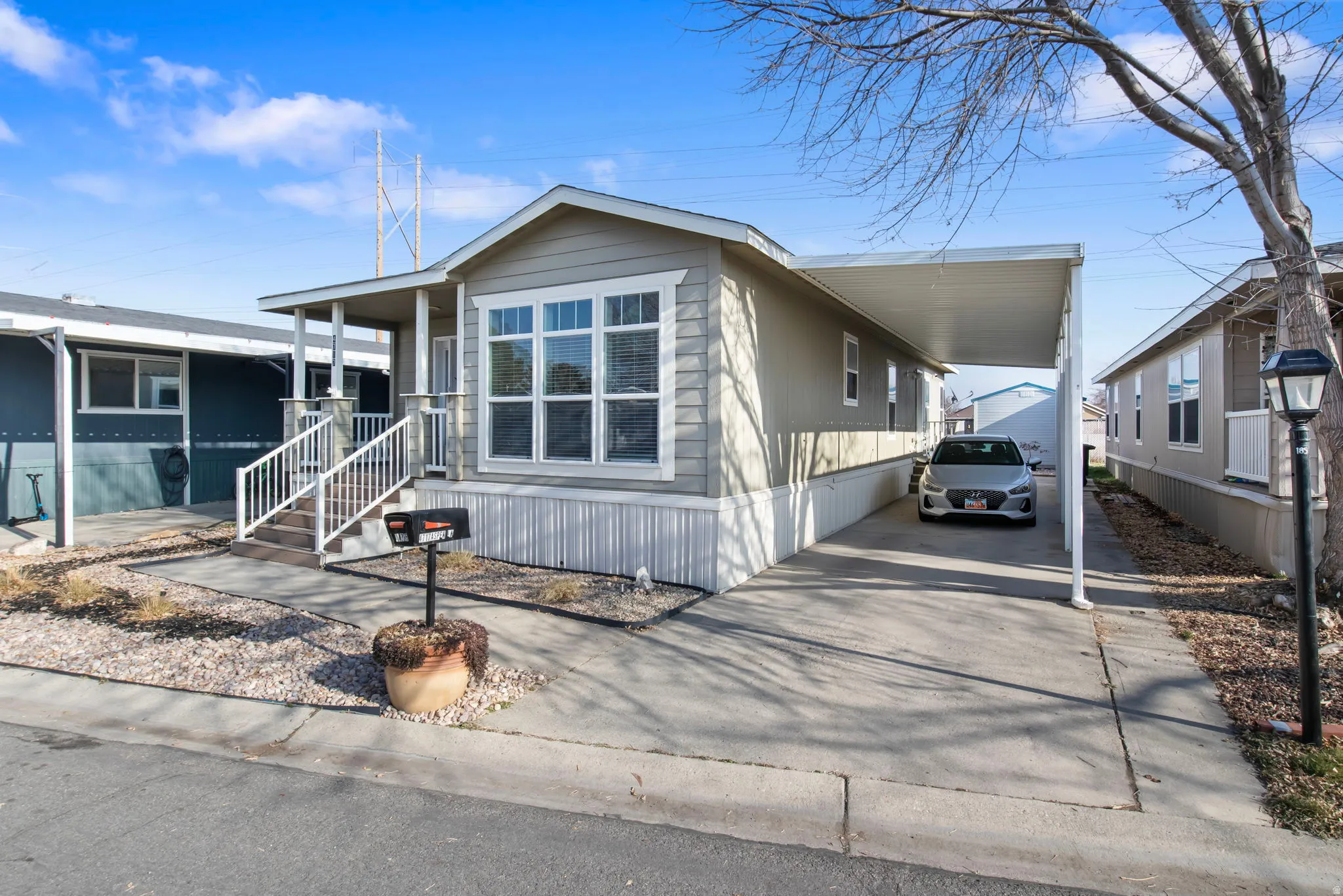 Manufactured / mobile home with an attached carport, concrete driveway, and covered porch