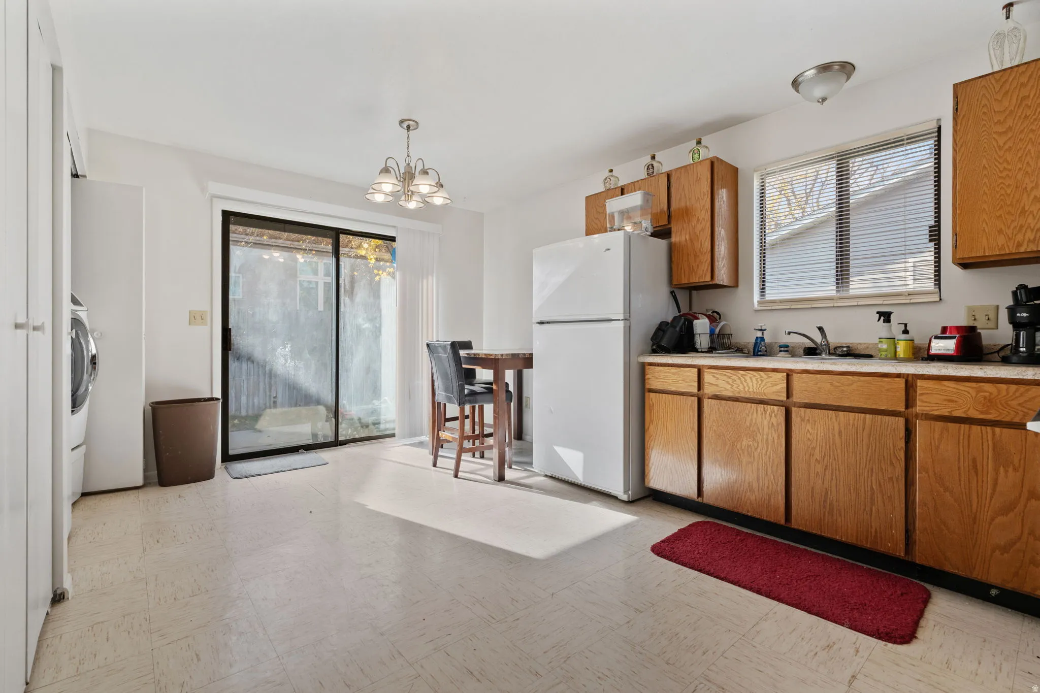Kitchen with brown cabinetry, light floors, light countertops, freestanding refrigerator, and pendant lighting