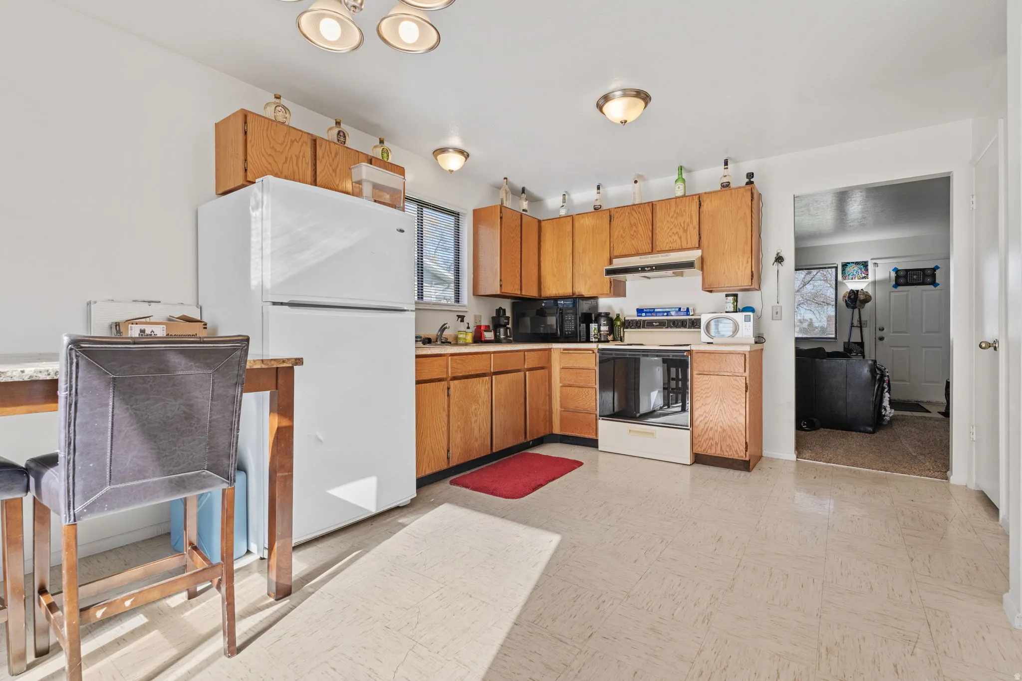 Kitchen featuring light flooring, light countertops, white appliances, wood finish cabinetry, and healthy amount of natural light