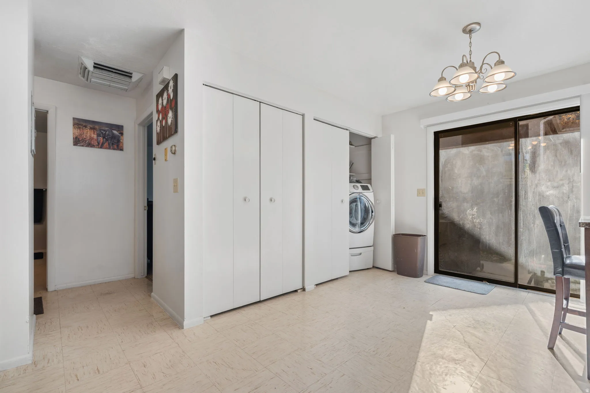 Washroom featuring tile patterned floors, cooling unit, a chandelier, and washer / dryer