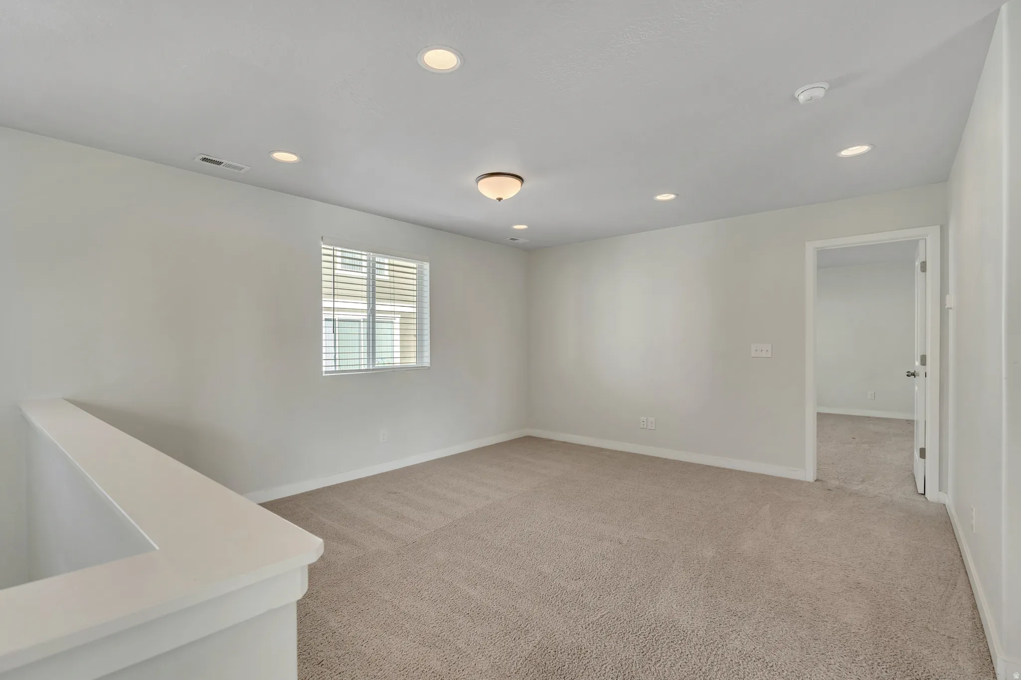 Empty room featuring recessed lighting and light carpet