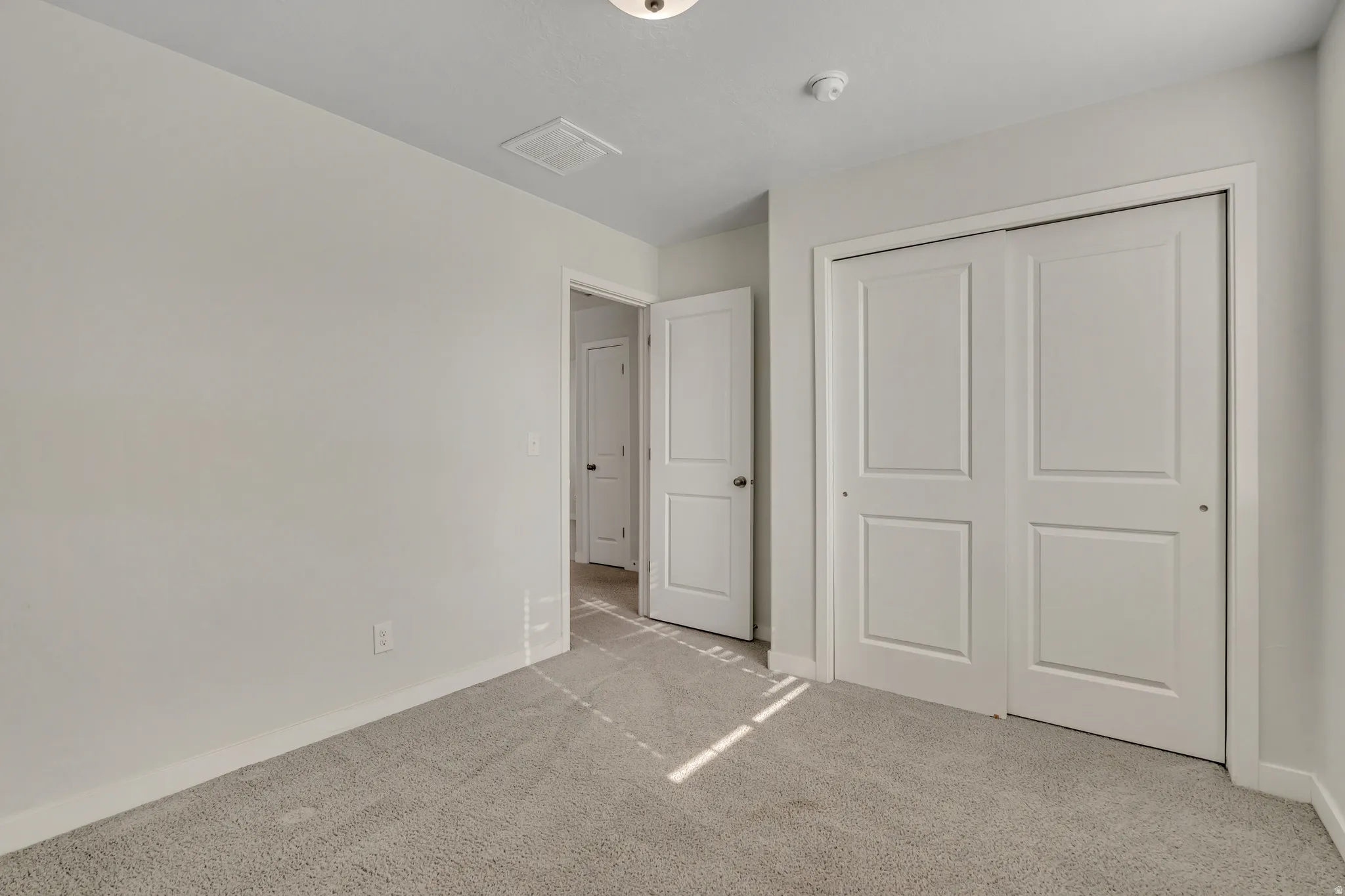 Unfurnished bedroom featuring light carpet and a closet