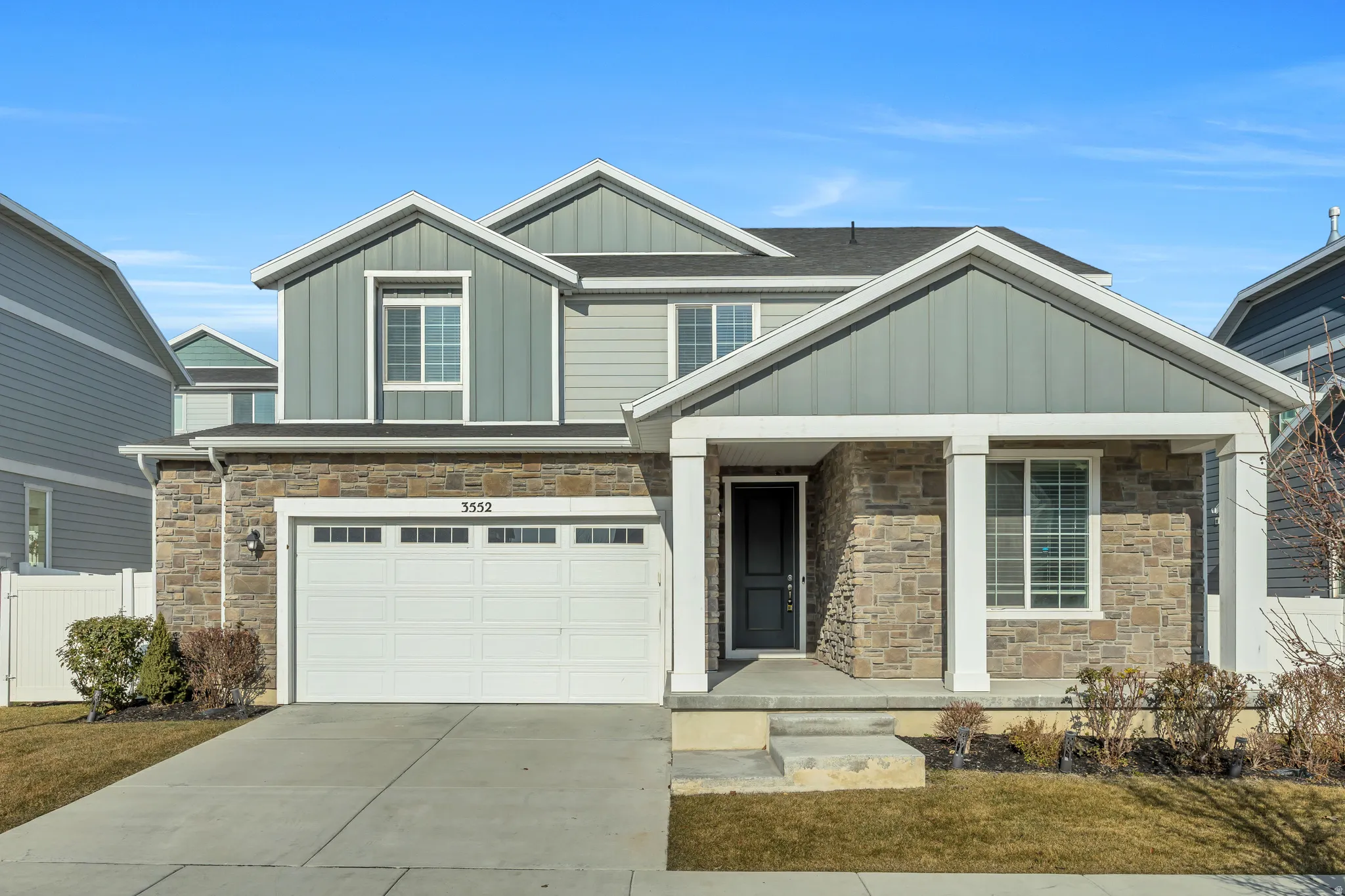 Craftsman-style home with board and batten siding, stone siding, concrete driveway, and a garage