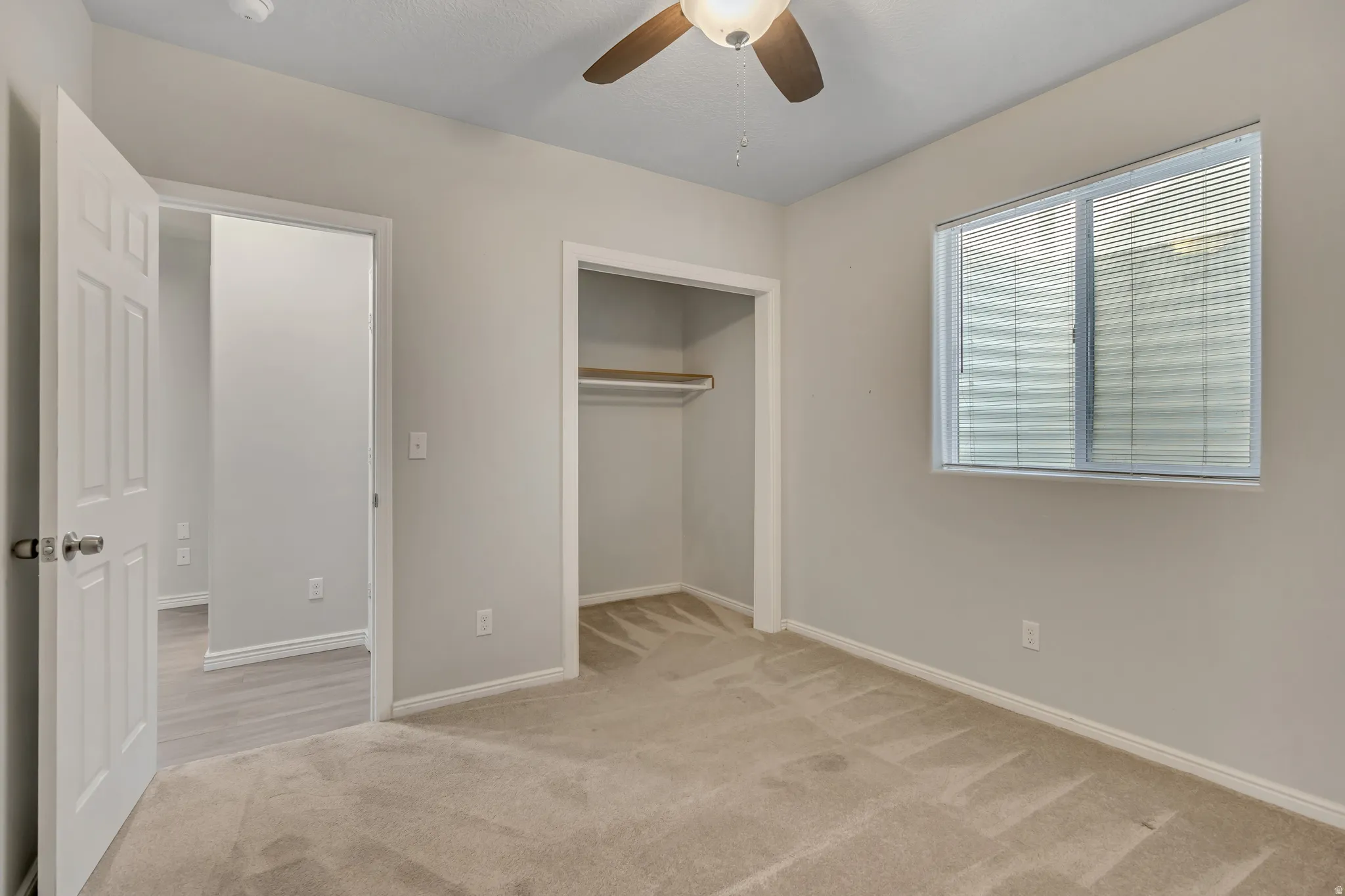 Unfurnished bedroom featuring a ceiling fan, light colored carpet, and a closet