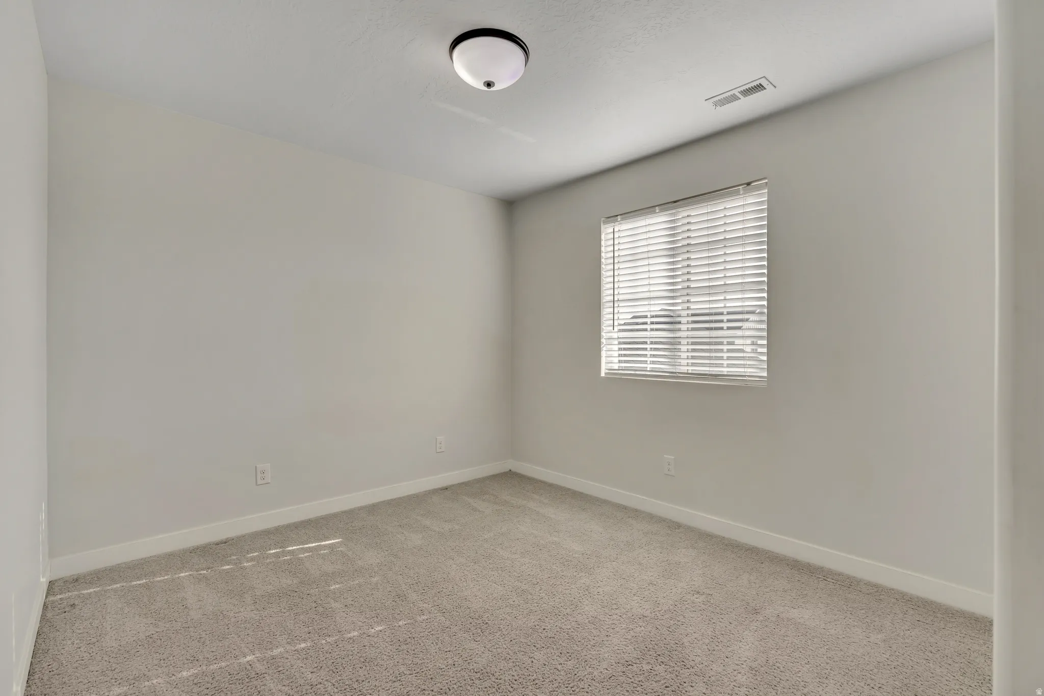 Empty room featuring light colored carpet and baseboards