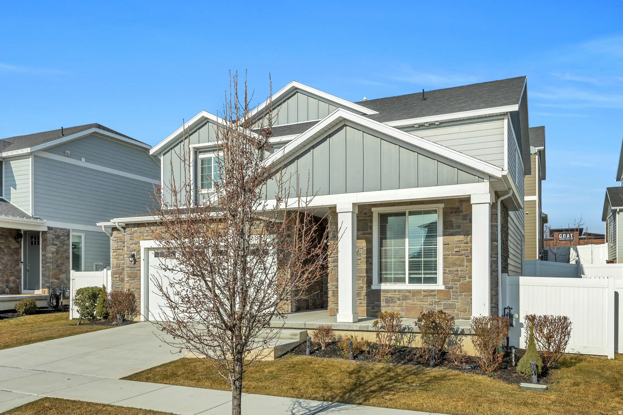 Craftsman house with covered porch, stone siding, board and batten siding, concrete driveway, and a garage