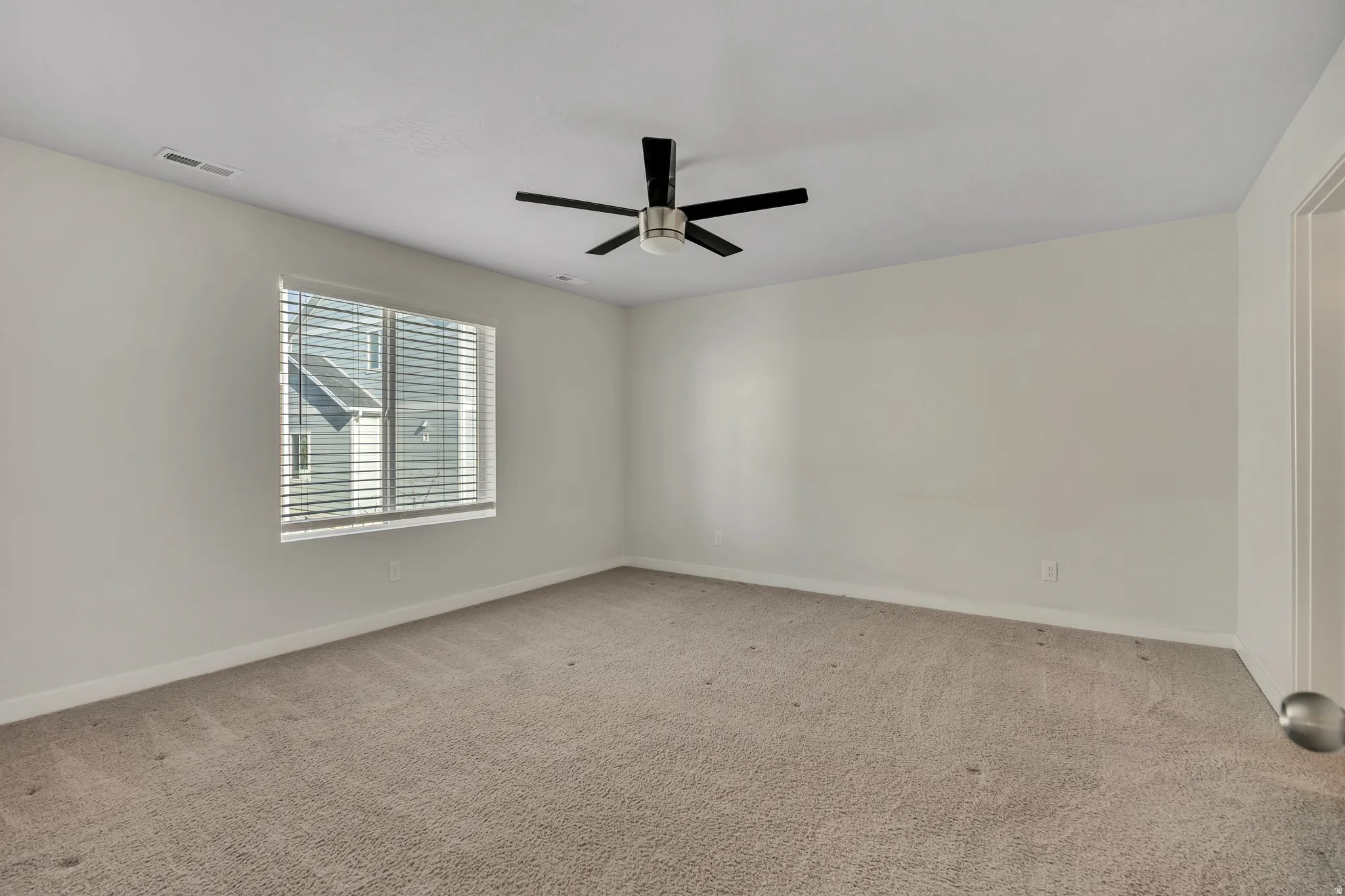 Unfurnished room with light colored carpet and a ceiling fan