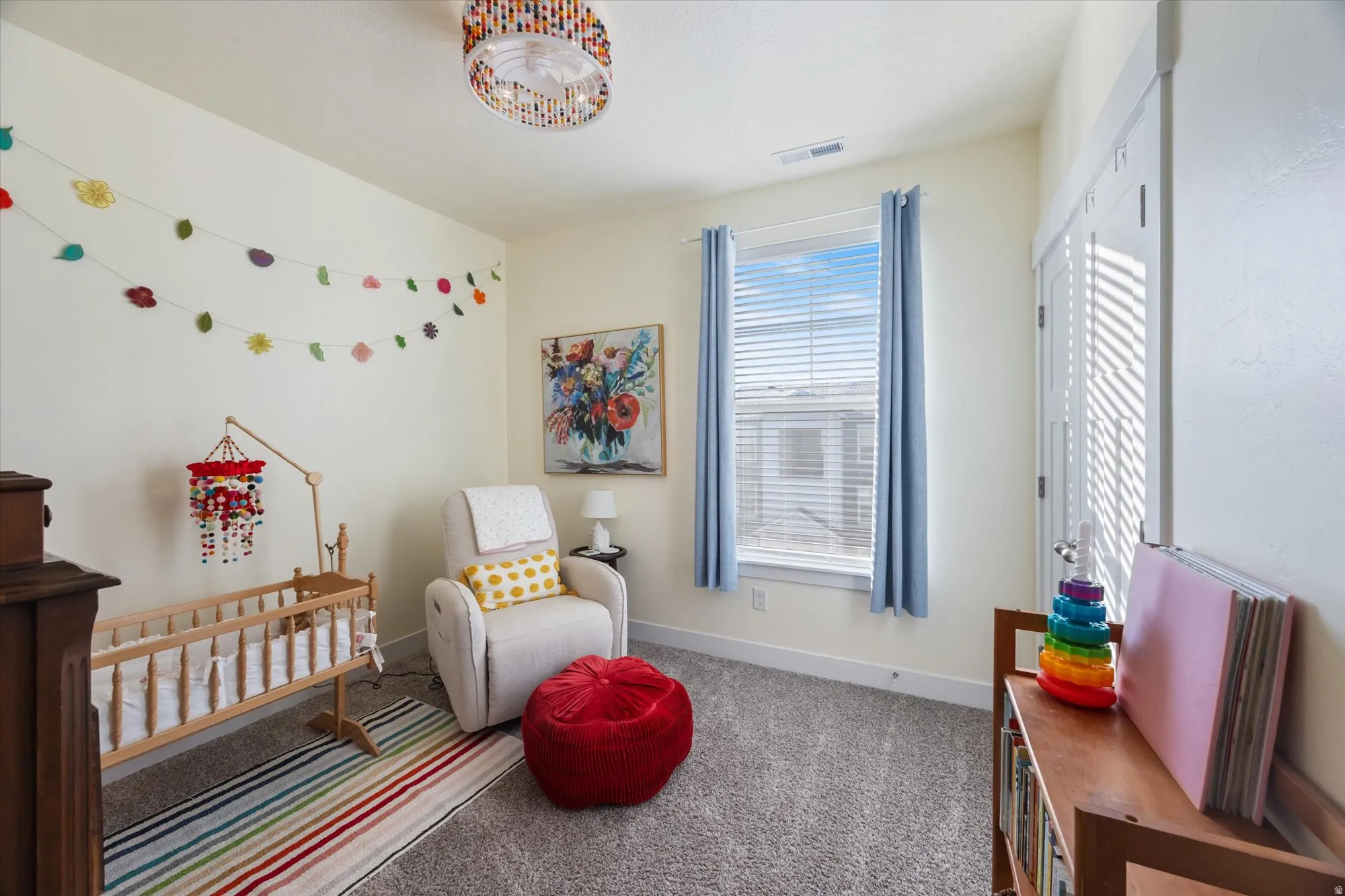 Carpeted bedroom with a crib and baseboards