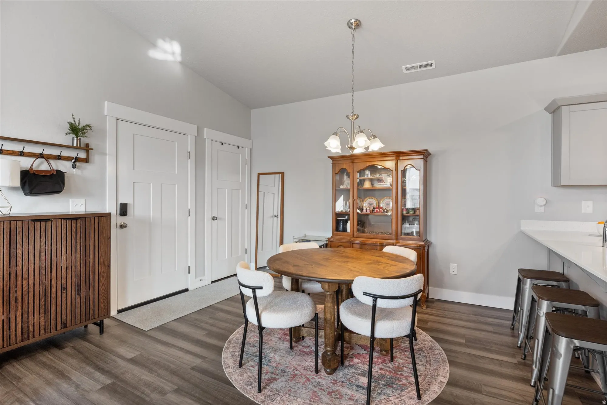 Dining space featuring dark wood-style flooring, a chandelier, and vaulted ceiling