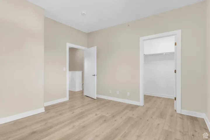 Unfurnished bedroom with a spacious closet and light wood-style flooring