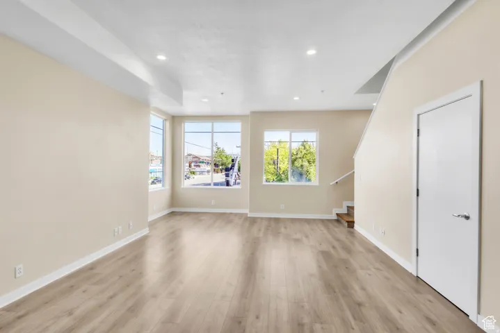 Unfurnished living room with stairs, light wood-type flooring, and recessed lighting
