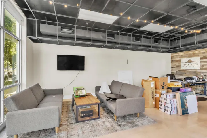 Living room featuring wood walls, finished concrete flooring, and an accent wall