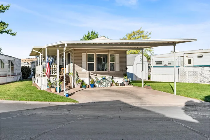 Manufactured / mobile home with a front lawn and a storage shed