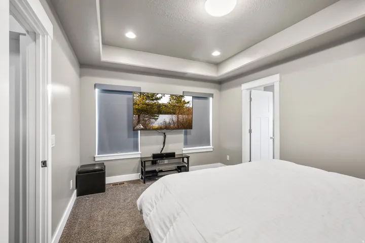 Carpeted bedroom with a tray ceiling, recessed lighting, and a textured ceiling