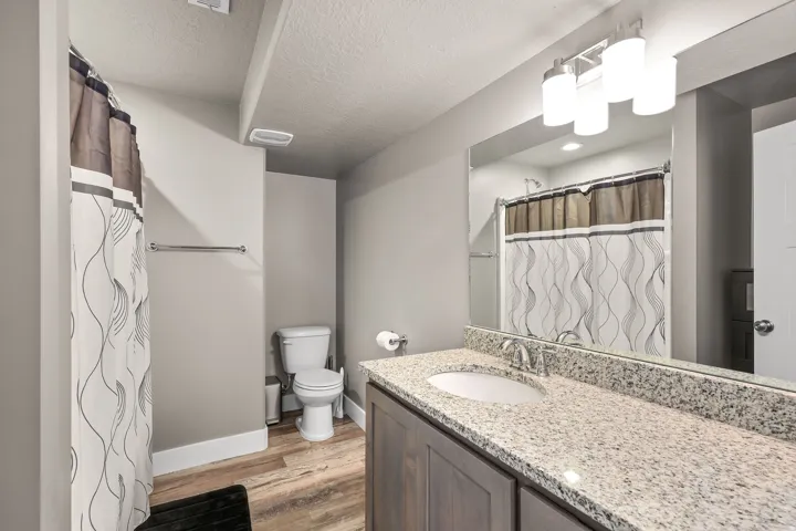Bathroom featuring curtained shower, vanity, light wood-style flooring, and a textured ceiling