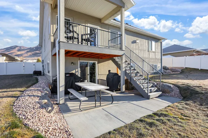 Rear view of property featuring a patio, a fenced backyard, stairs, stucco siding, and a balcony