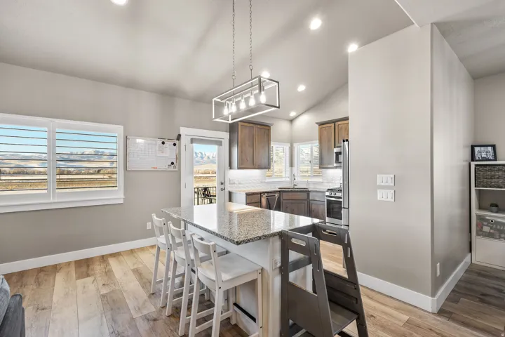 Kitchen featuring vaulted ceiling, light stone counters, a kitchen breakfast bar, recessed lighting, and a kitchen island
