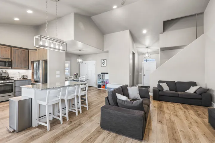 Kitchen featuring a kitchen bar, light stone countertops, appliances with stainless steel finishes, high vaulted ceiling, and open floor plan