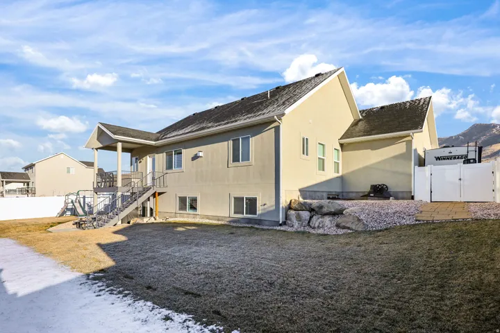 Back of property featuring stairs, a gate, and stucco siding
