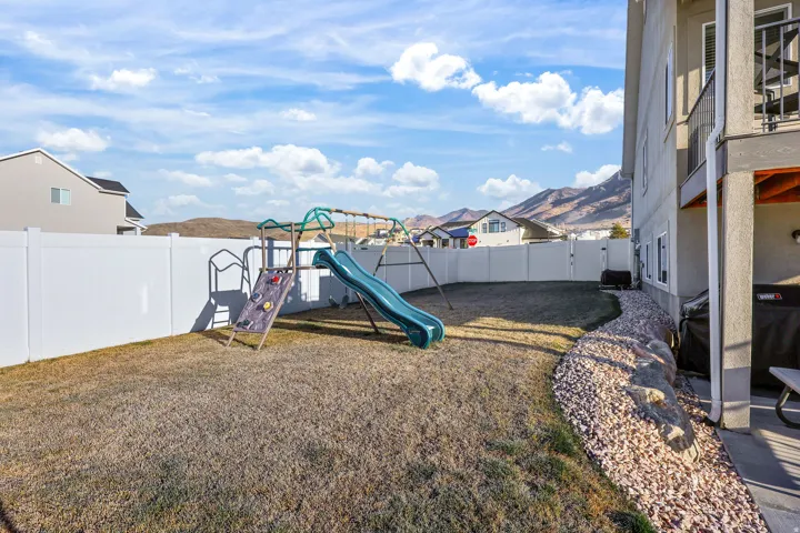 Fenced backyard featuring a playground and a residential view