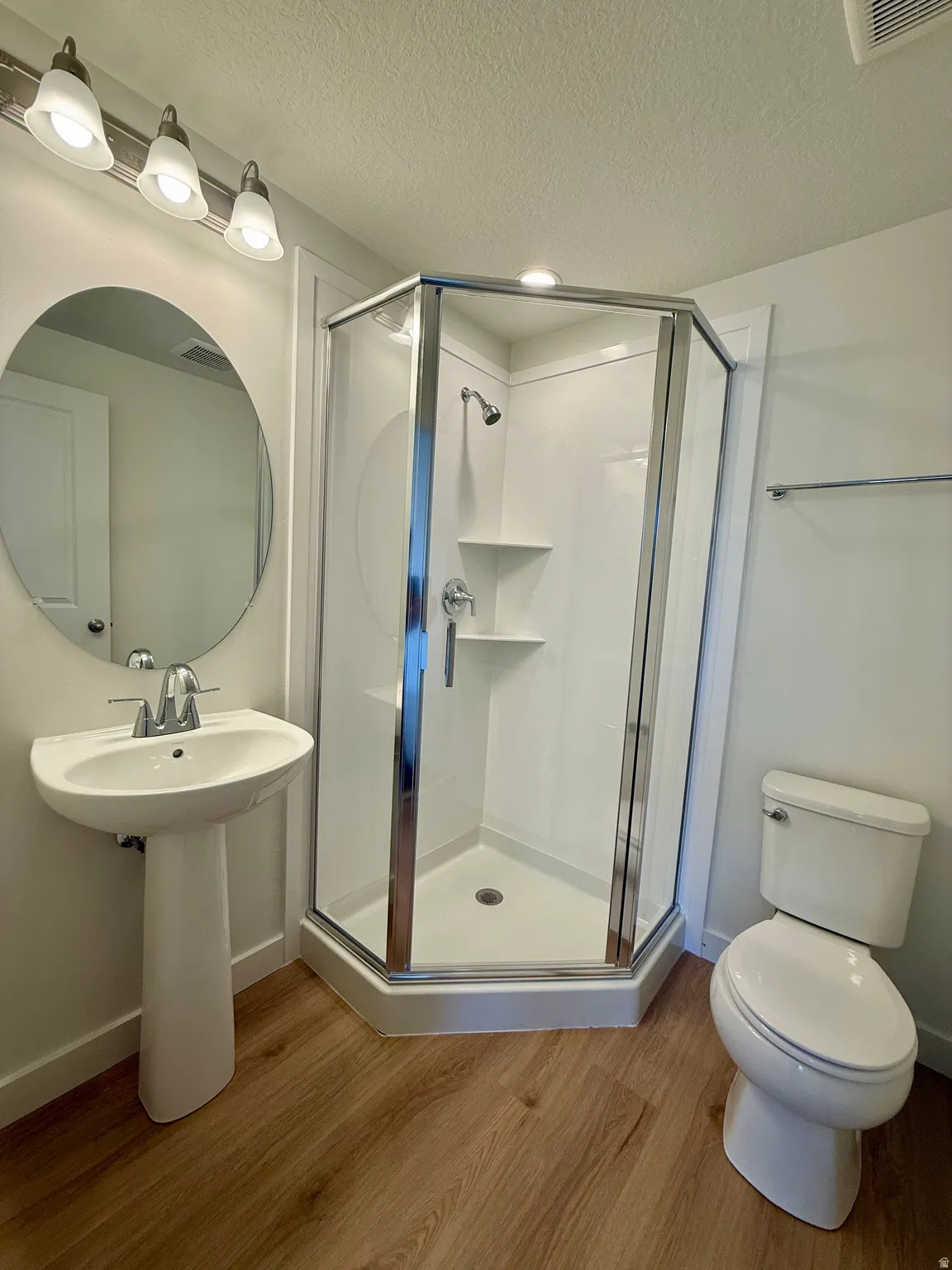 Bathroom featuring a stall shower, wood finished floors, and a textured ceiling