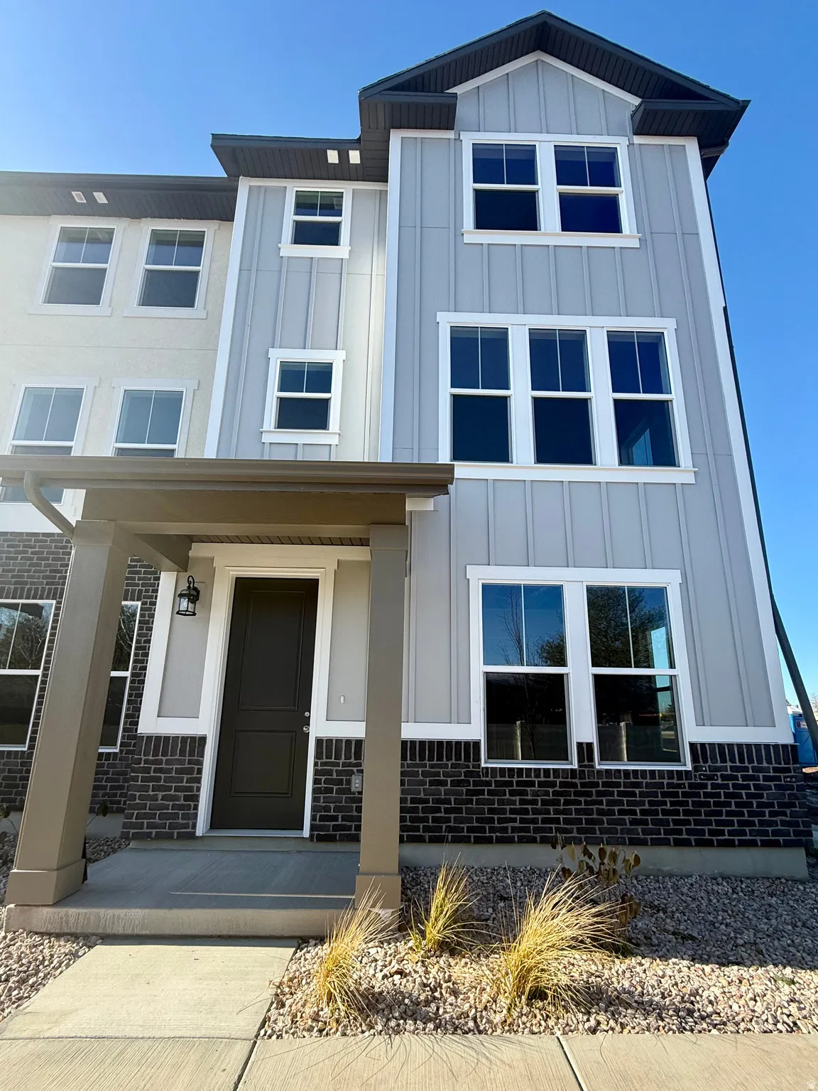 View of front of property with board and batten siding, a porch, and brick siding