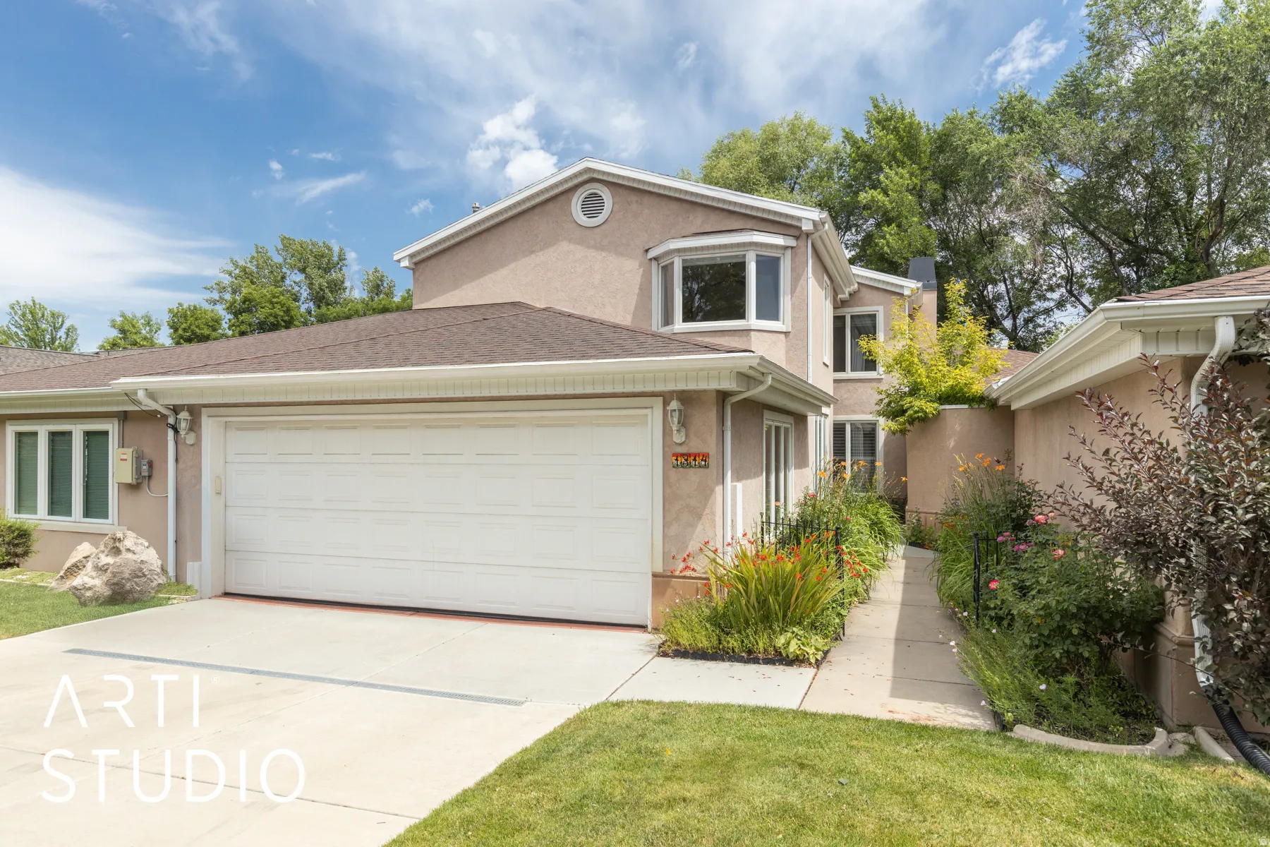 Traditional-style house with driveway, an attached garage, stucco siding, a front lawn, and roof with shingles