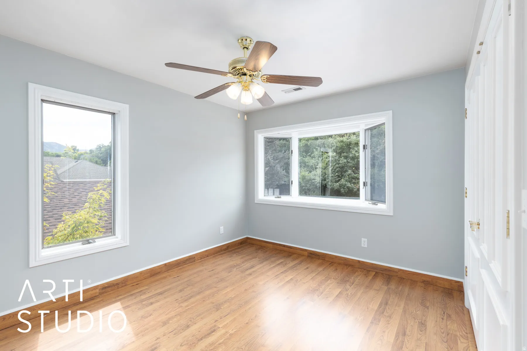 Spare room featuring light wood-type flooring, healthy amount of natural light, and ceiling fan