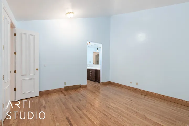 Unfurnished bedroom with lofted ceiling, light wood-type flooring, and ensuite bathroom